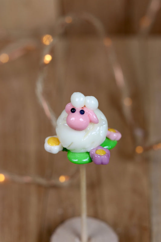 Sucette sculptée en forme de mouton à la banane et à la fraise dans une prairie fleurie multifruit