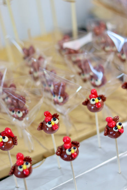 Sucette en sucre cuit sculptée en forme de poule au cacao et à la framboise. Dans l'atelier de fabrication