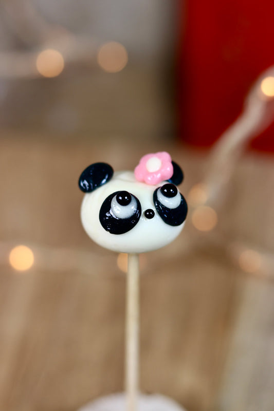 Sucette sculptée en forme de tête de panda vanille cola avec une fleur sur la tête. En gros plan