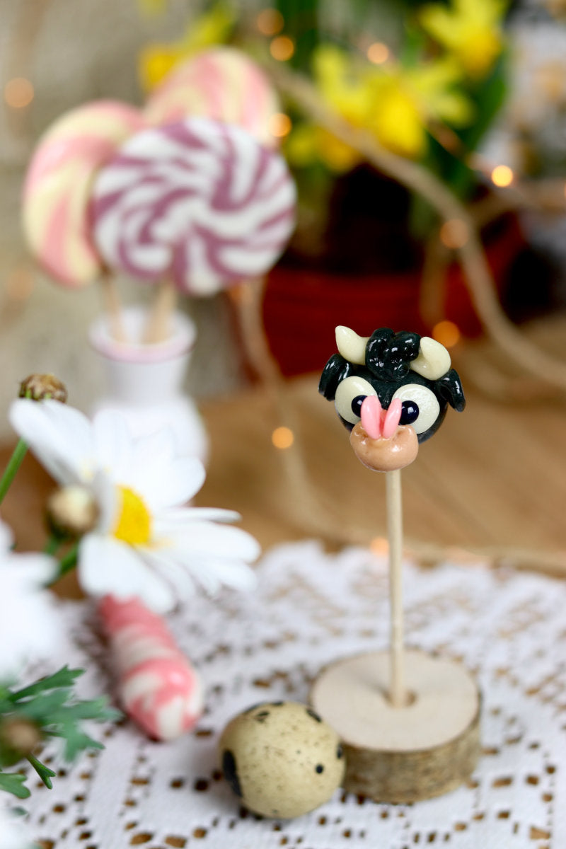 Sucette sculptée en forme de taureau au cola avec un papillon sur le nez. Dans un déco printanier