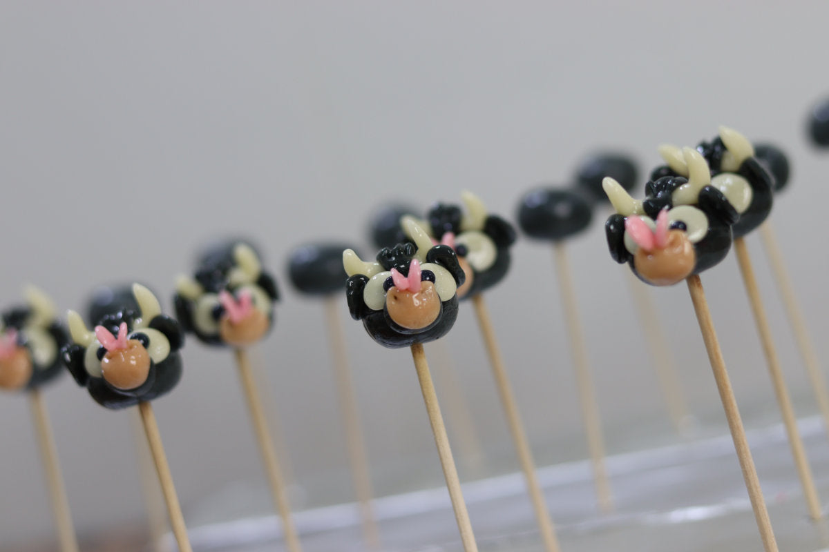 Sucette sculptée en forme de taureau au cola avec un papillon sur le nez. Dans l'atelier de fabrication 