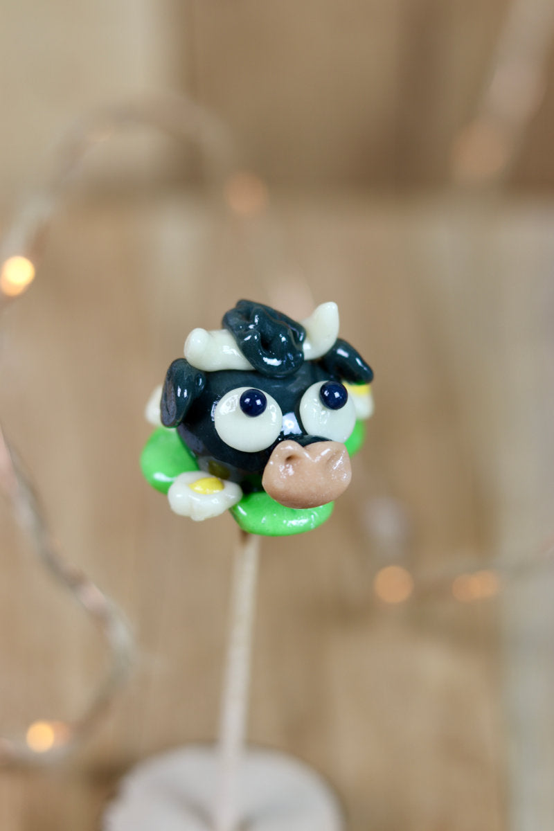 Sucette sculptée en forme de taureau dans une prairie à la pomme entouré de pâquerettes. En sucre cuit. 