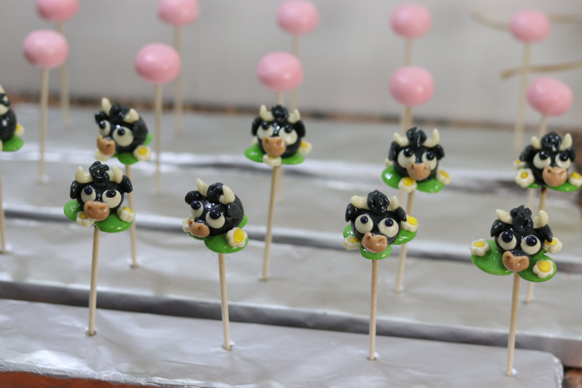 Sucette sculptée en forme de taureau dans une prairie à la pomme entouré de pâquerettes. En sucre cuit. Dans l'atelier de fabrication