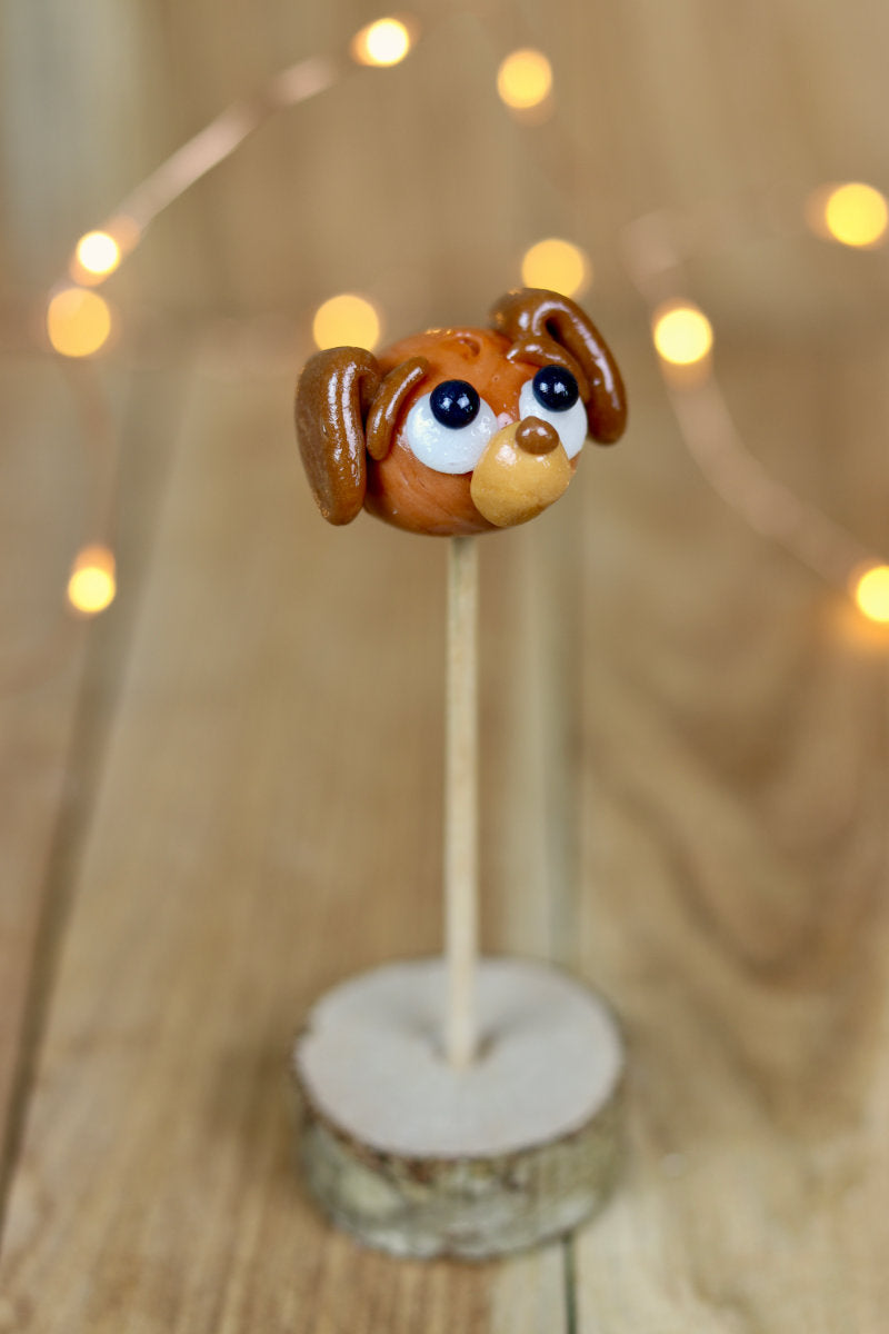 Sucette sculptée en forme de teckel au cola et au caramel beurre salé dans un décor féérique