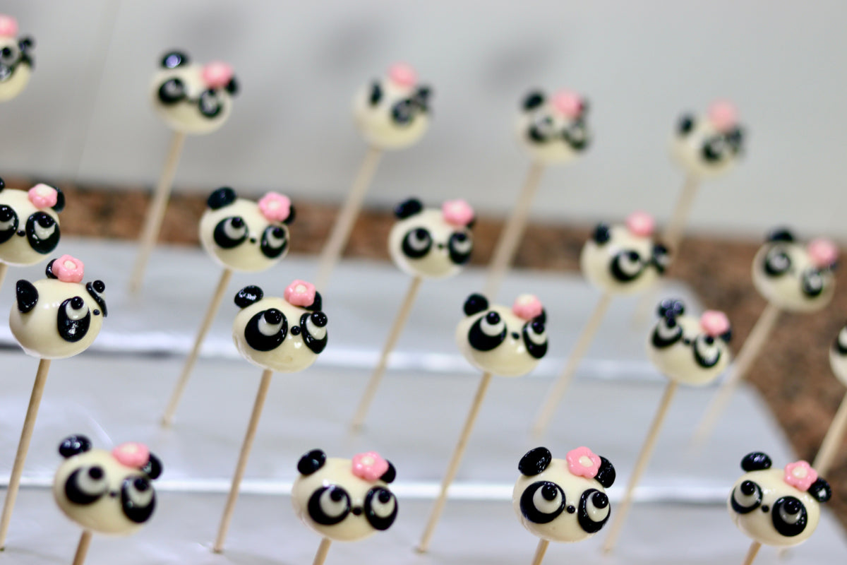 Sucette sculptée en forme de tête de panda vanille cola avec une fleur rose sur la tête. Dans l'atelier de fabrication