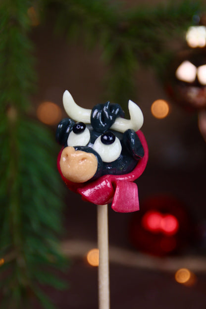 Une sucette en forme de taureau avec une écharpe à la cerise en gros plan