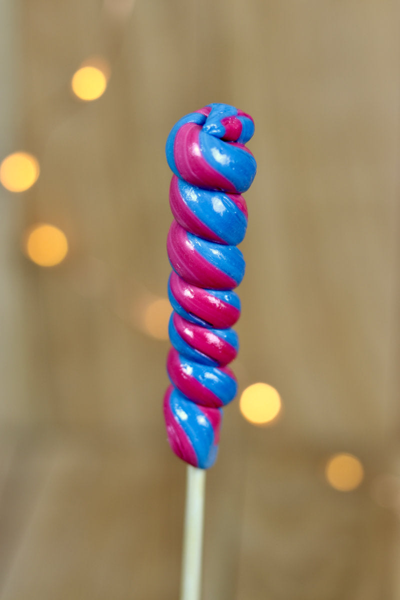 Une sucette torsade réalisée à la main, en sucre cuit aromatisé à la myrtille et à la cerise. Un tourbilon de deux couleurs, bleu et Bourdeau. 