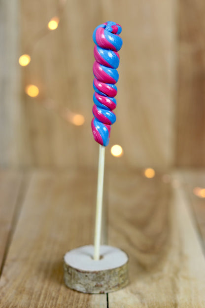 Une sucette torsade réalisée à la main, en sucre cuit aromatisé à la myrtille et à la cerise. Un tourbilon de deux couleurs, bleu et Bourdeau. 