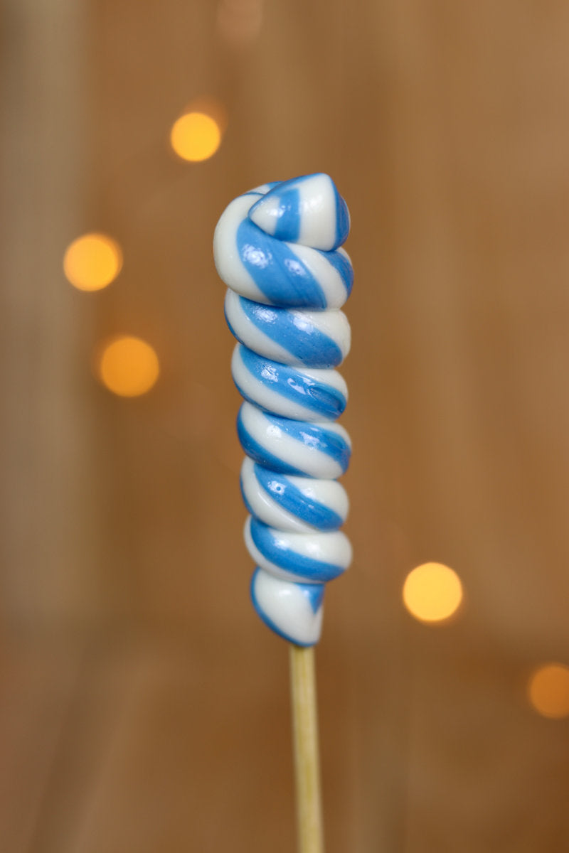 Une sucette torsade fabriqué à la main en sucre cuit aromatisé à la myrtille et au citron. Un tourbillon blanc et bleu