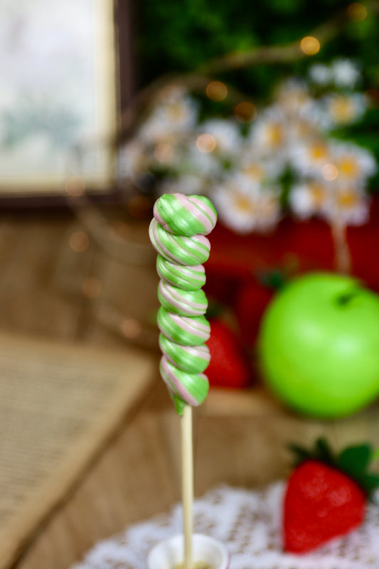 Sucette torsade artisanale aux parfums pomme et fraise, vue rapprochée sur les spirales colorées.
