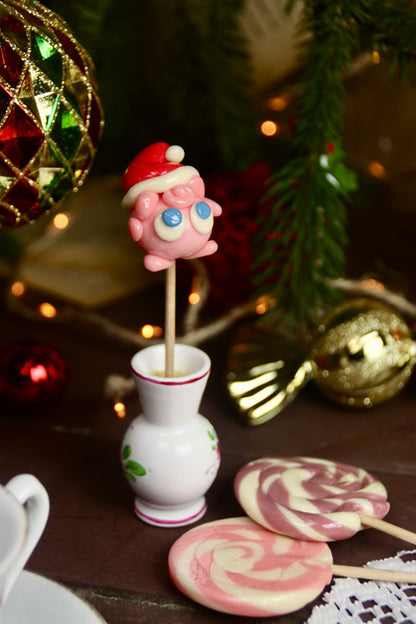 Une sucette en forme de rondoudou de noel dans un décor féérique de noel