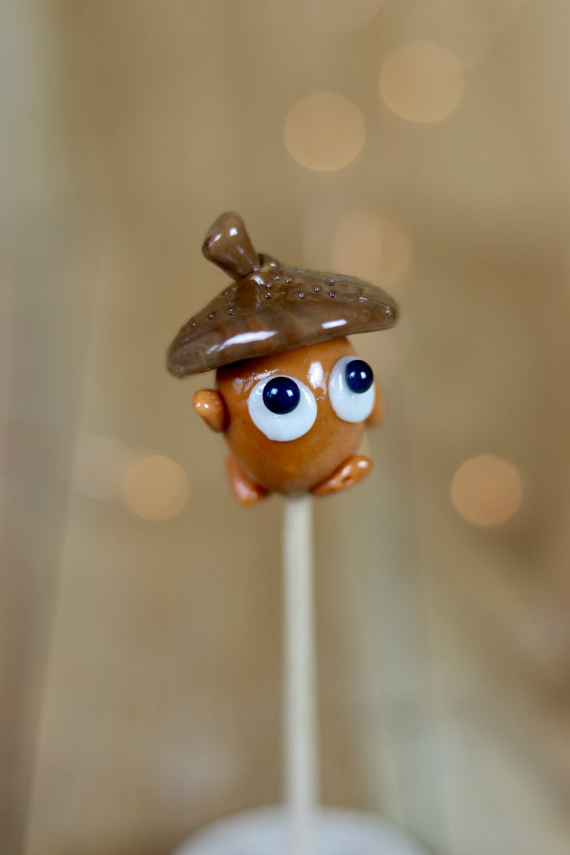Une sucette sculptée en forme de gland au cola, pour une décoration automne ou forêt