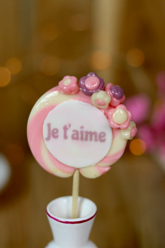 sucette en forme de spirale écrit je t'aime au centre, avec des petites fleurs dessus