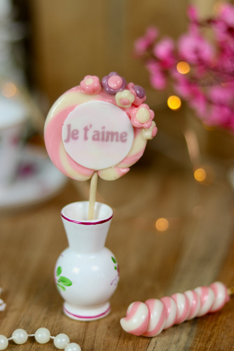 sucette en forme de spirale écrit je t'aime au centre, avec des petites fleurs dessus