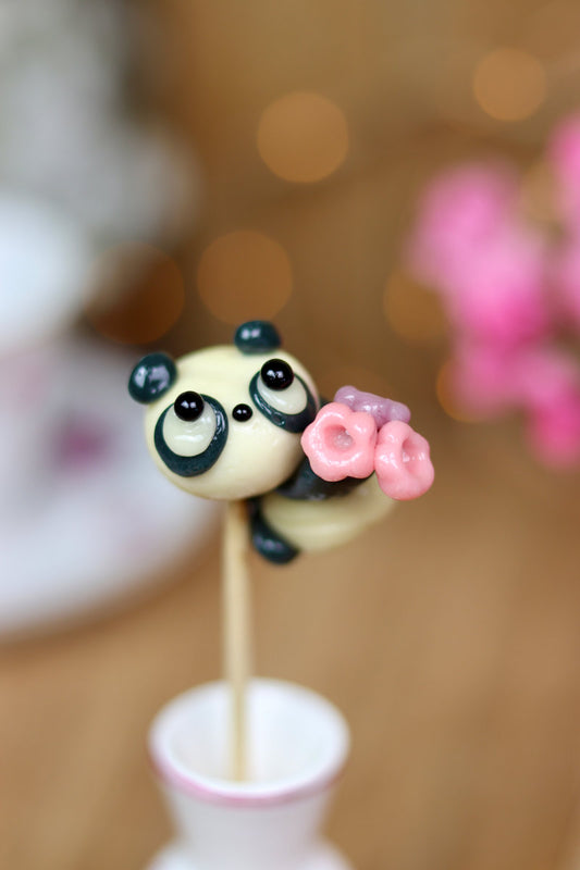 Sucette cola vanille en forme de panda qui offre un bouquet de fleur