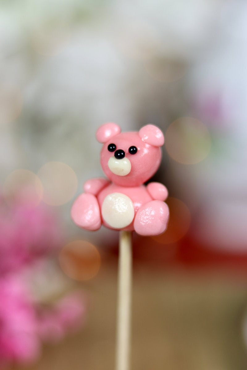 une sucette sculptée en forme de peluche rose à la fraise