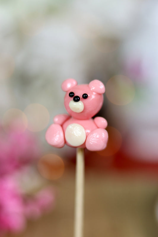 une sucette sculptée en forme de peluche rose à la fraise