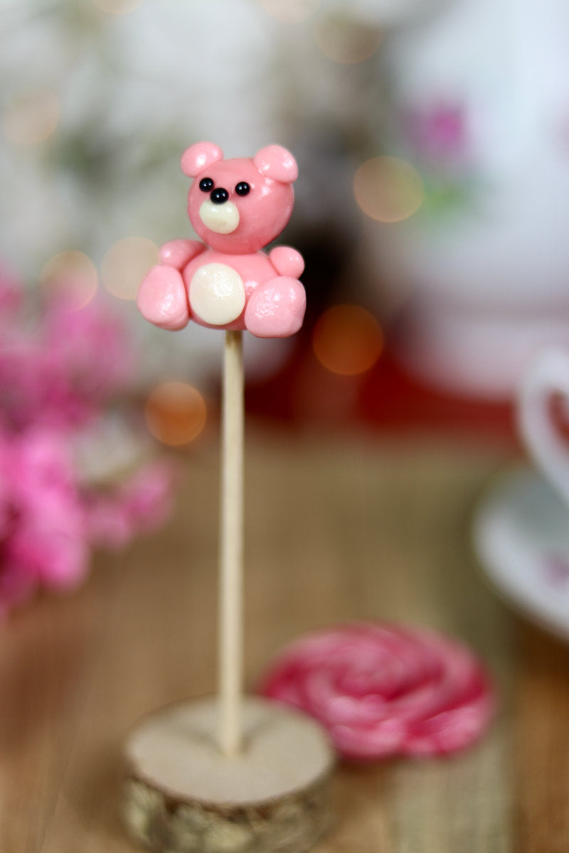 une sucette sculptée en forme de peluche rose à la fraise
