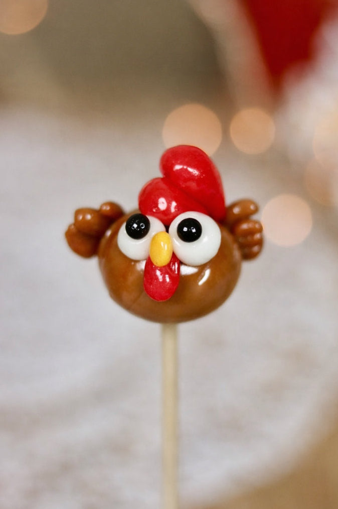 Une sucette sculptée en forme de poule marron en gros plan, au cola et à la cerise