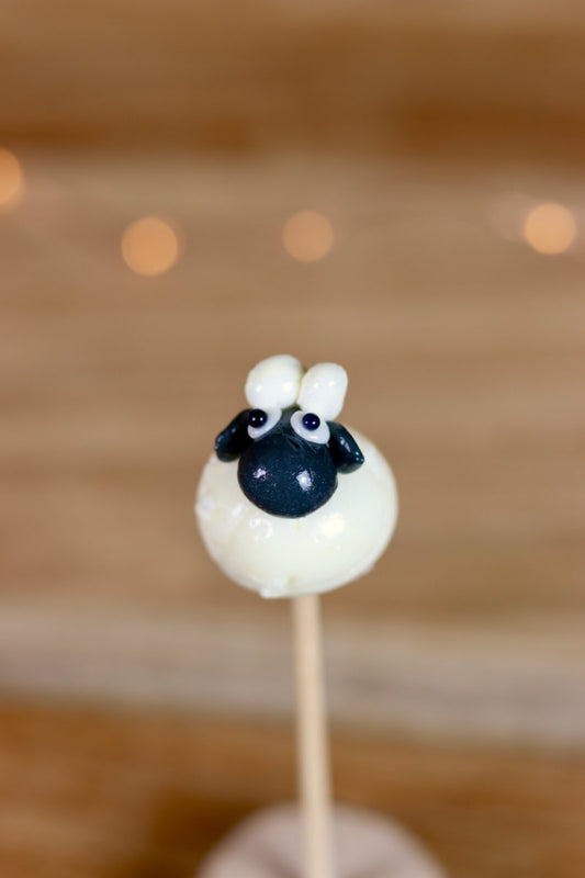 Une sucette sculptée en forme de mouton avec une tête noir au cola et le corp en blanc au citron
