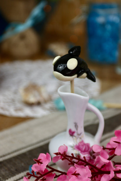 Sucette orque vanille cola dans un décor marin, entourée de coquillages et d’éléments océaniques, parfaite pour un thème océan ou une décoration gourmande.