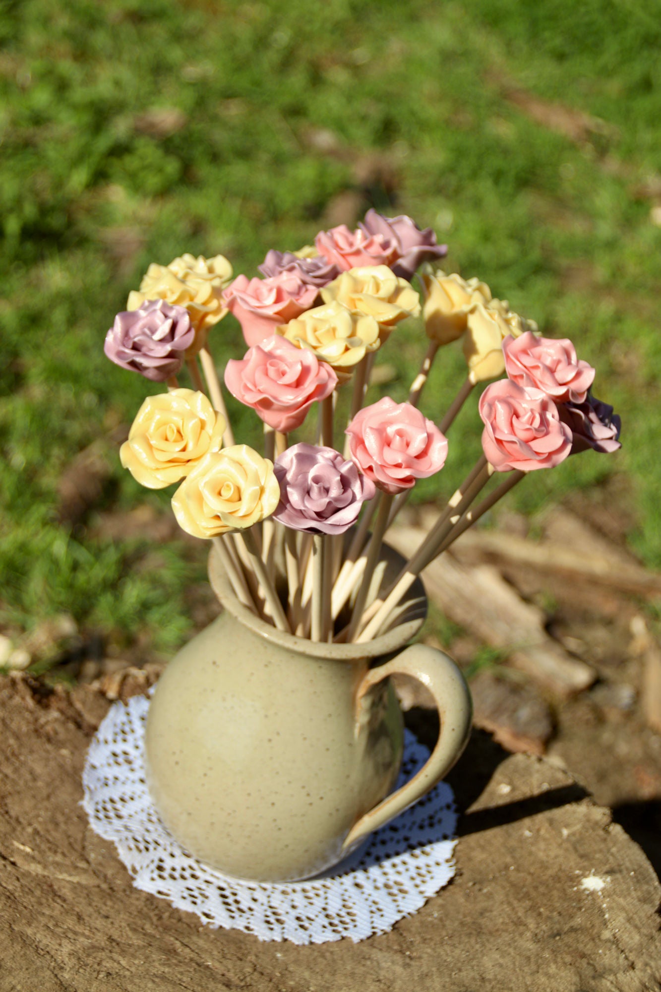 Un bouquet de sucettes en forme de fleurs dans un vase, dans un jardin  avec une ambiance pratanier. Des fleurs en sucre cuit aromatisées avec des arômes naturels.